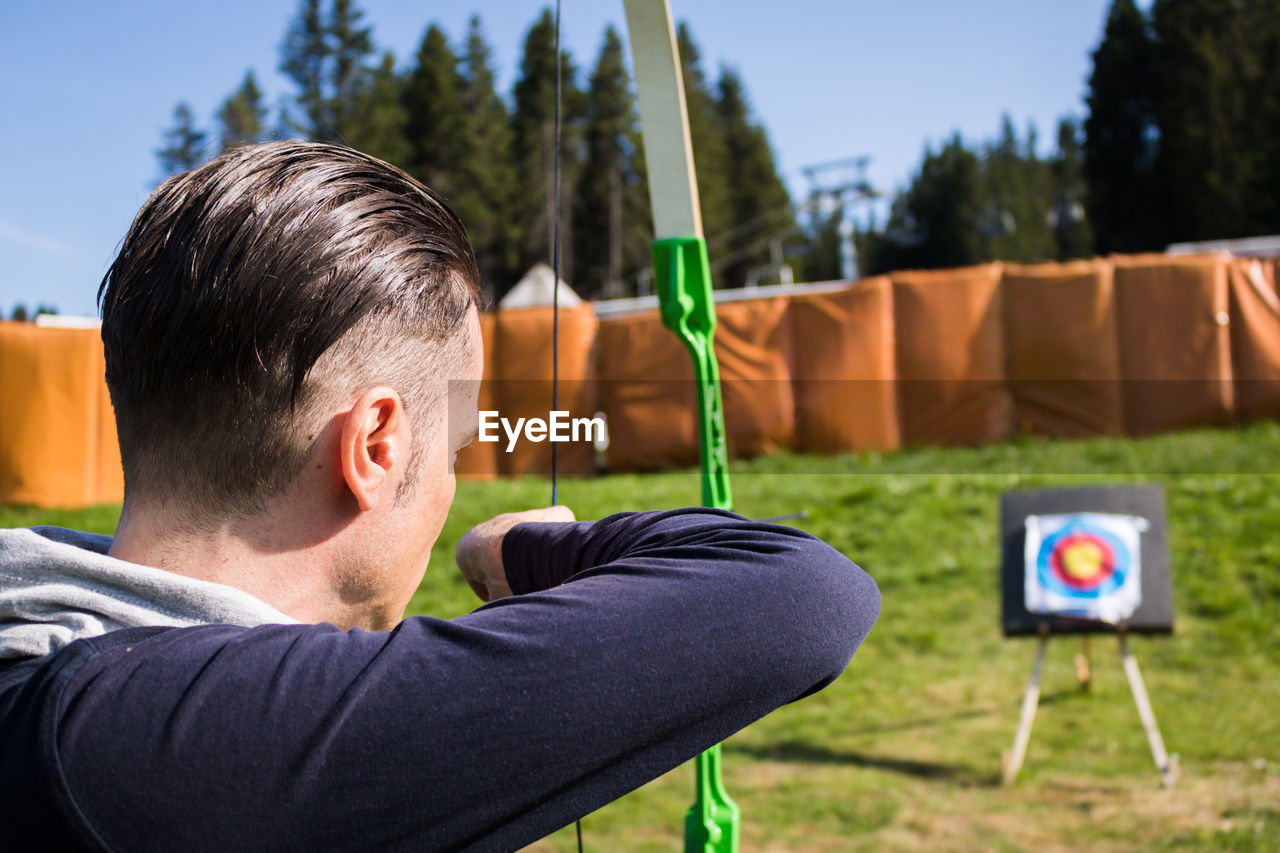 Man aiming bow while standing outdoor