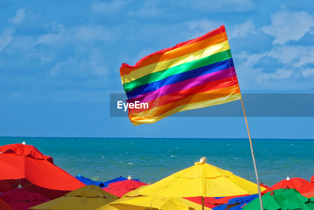 Multi colored flag on beach against sky