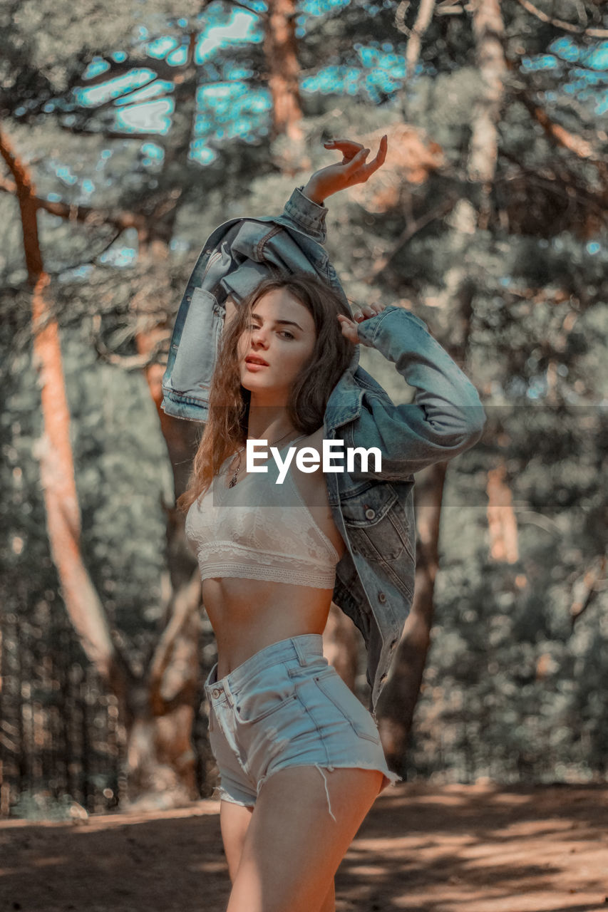 Midsection of woman standing by tree in forest