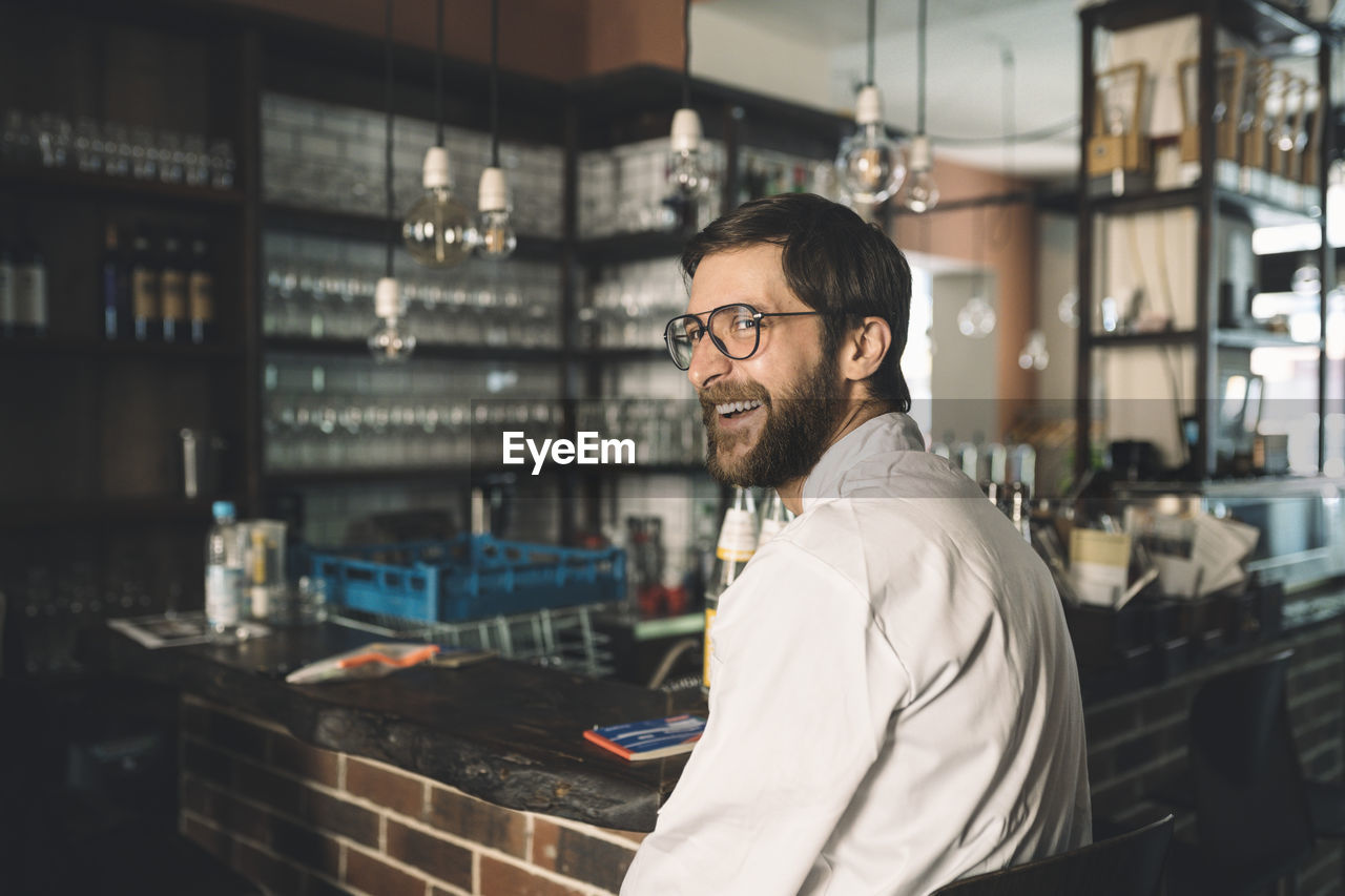 Side view of happy chef sitting in restaurant