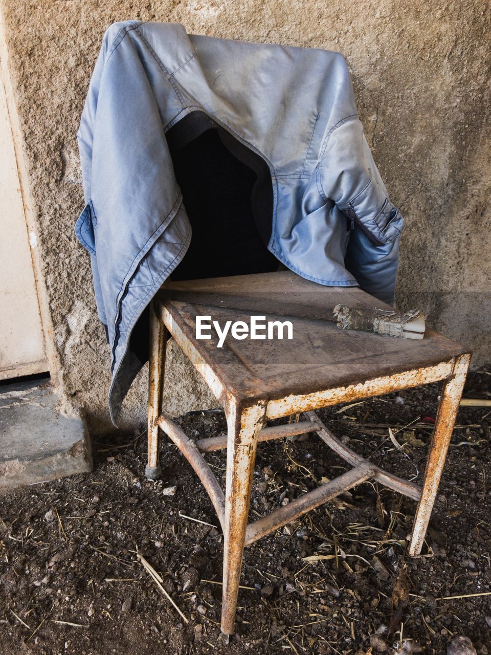 Old jacket on wooden chair against wall