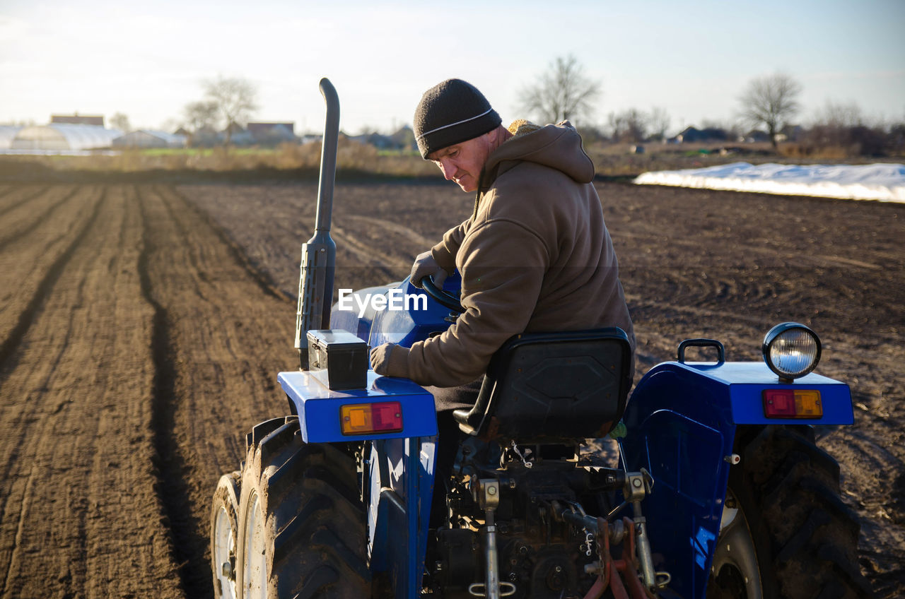 Senior farmer cultivating the farm field on a tractor. seasonal worker. recruiting workers