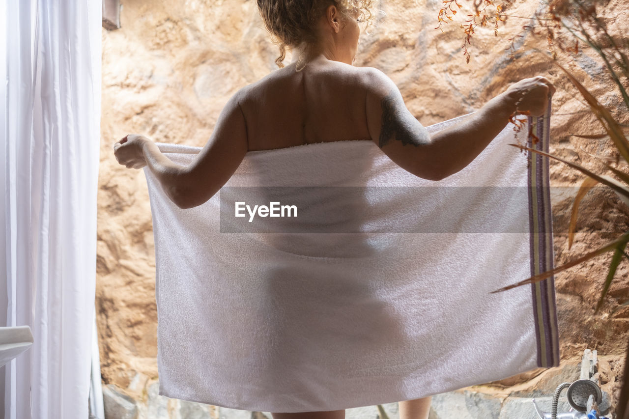 Rear view of woman holding towel in bathroom