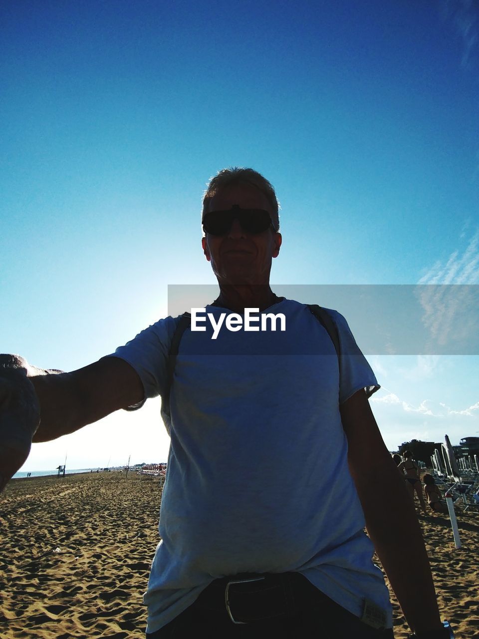 MAN STANDING AT BEACH AGAINST CLEAR SKY