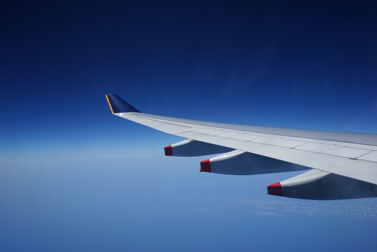 Cropped airplane wing against clear blue sky