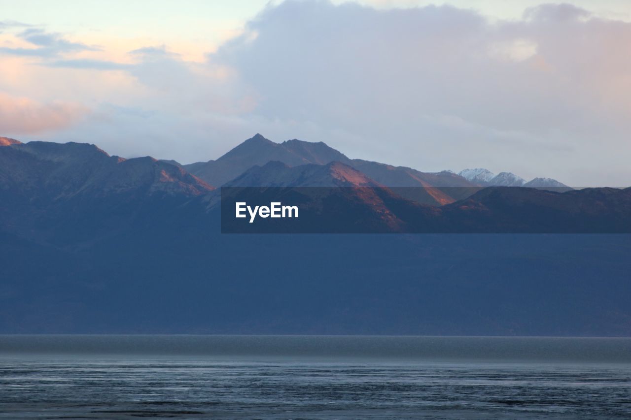 Scenic view of sea and mountains against sky