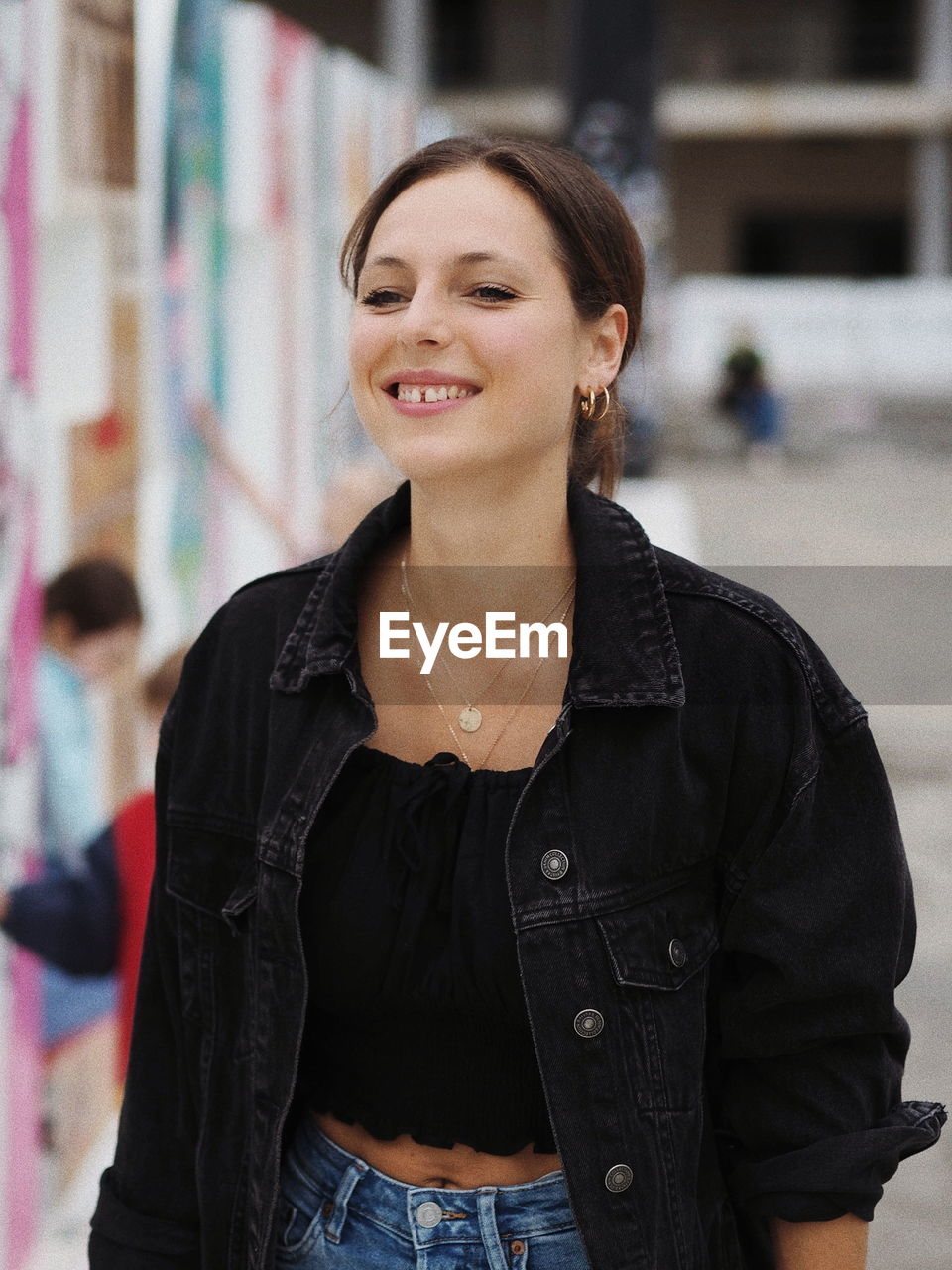 PORTRAIT OF SMILING WOMAN STANDING OUTDOORS