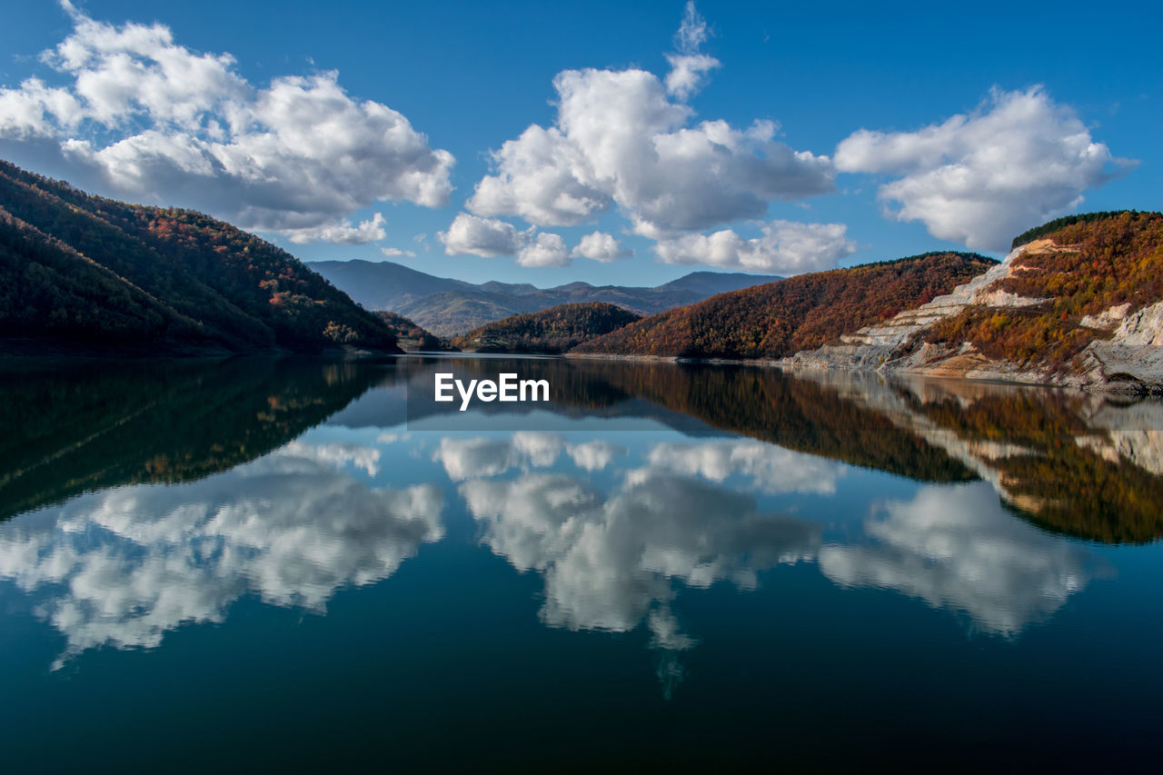 Scenic view of lake and mountains against cloudy sky