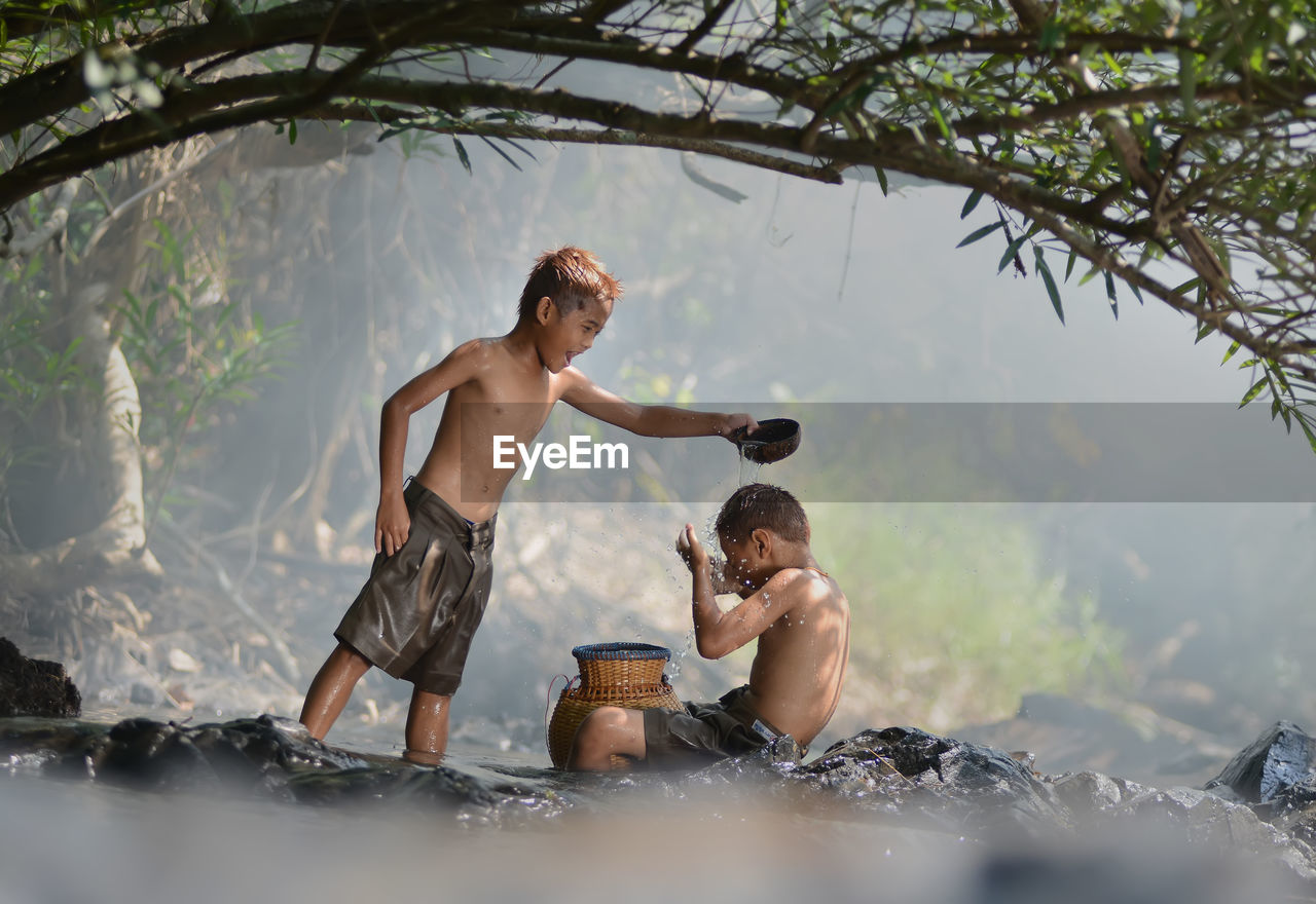 Boy bathing brother in forest