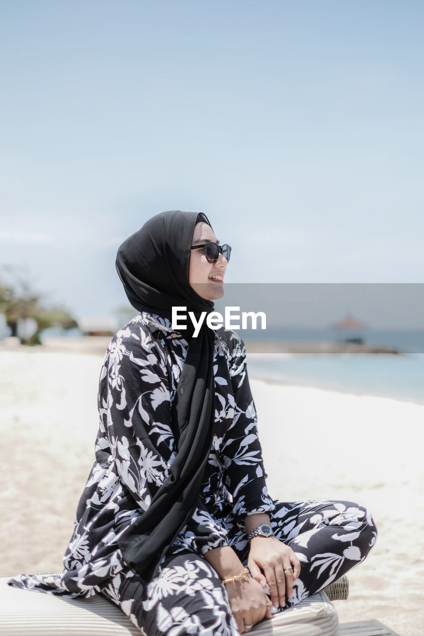 Woman wearing sunglasses sitting at beach