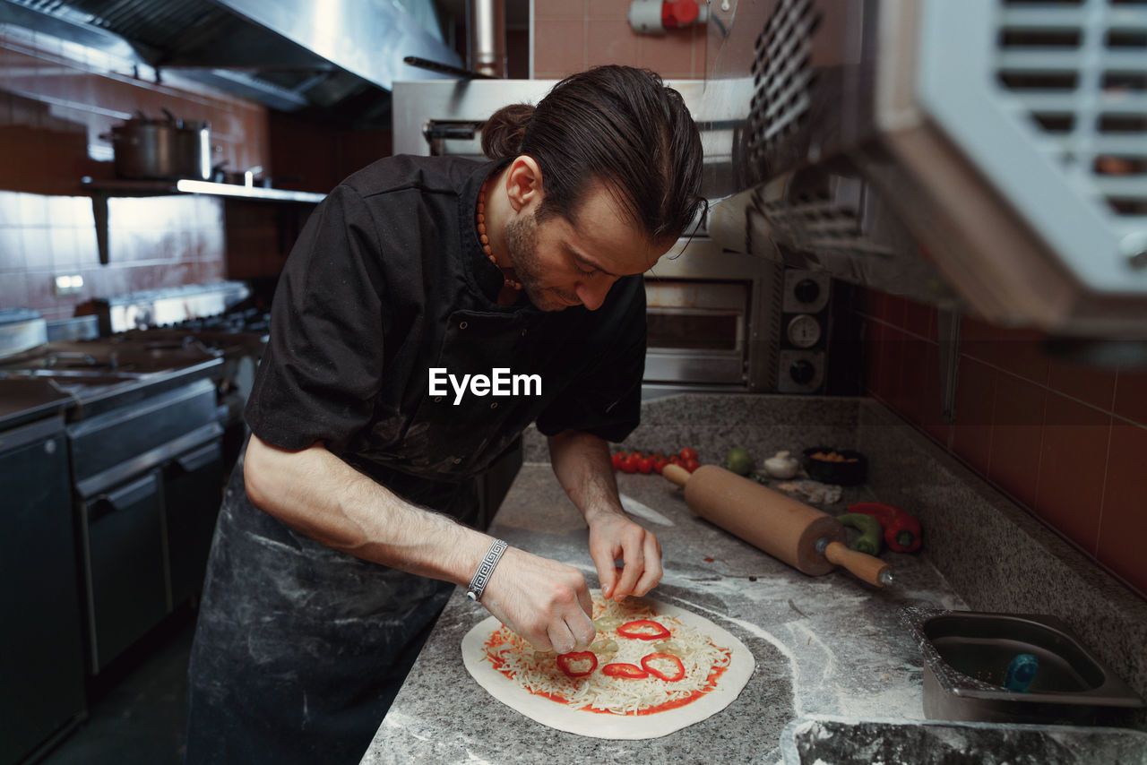 Fresh italian pizza making process. man making pizza at the kitchen