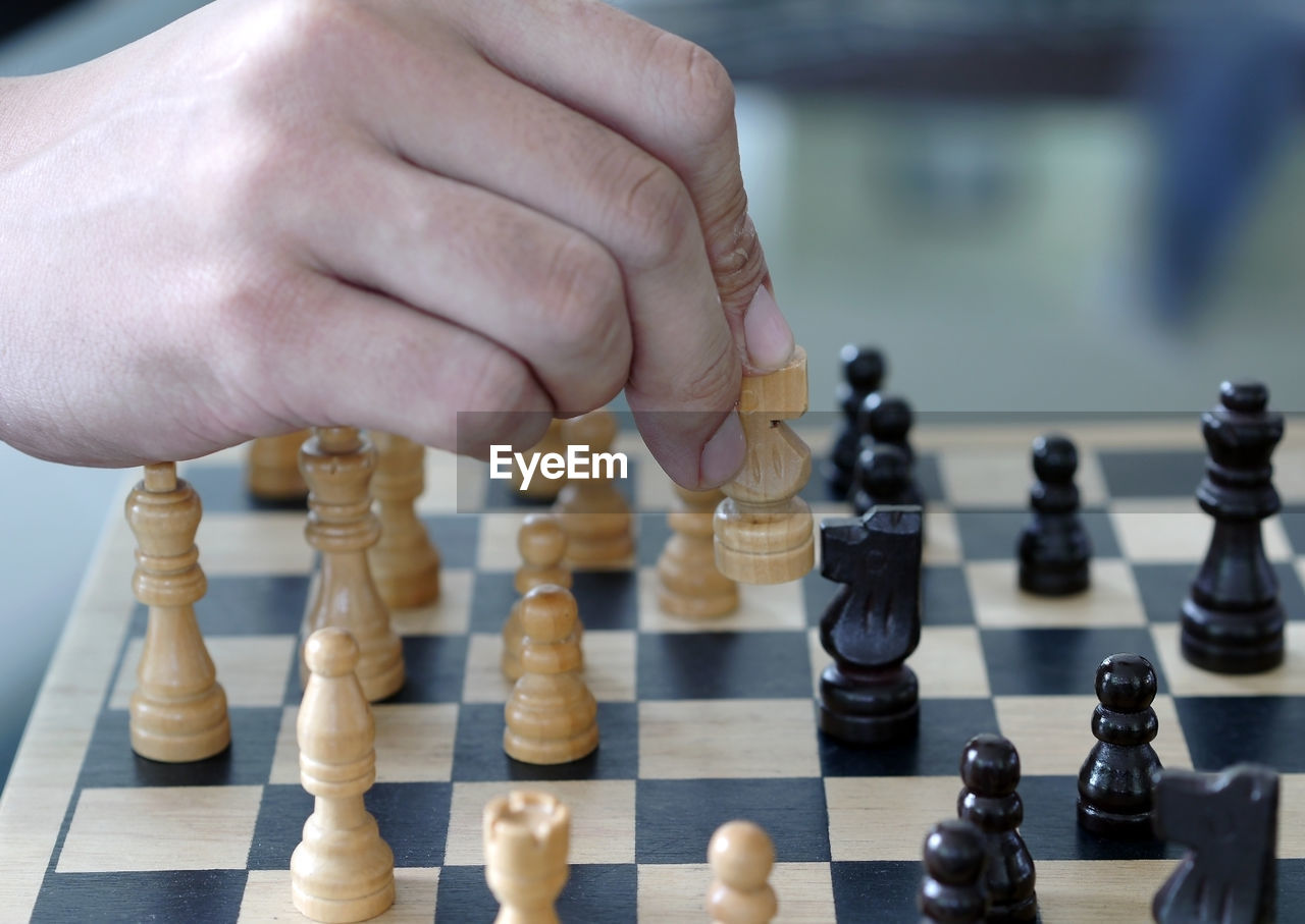 CLOSE-UP OF HUMAN HAND PLAYING WITH CHESS