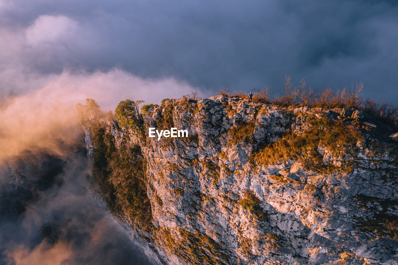 High angle view of man standing on mountain ridge rising above the clouds, hallein, austria