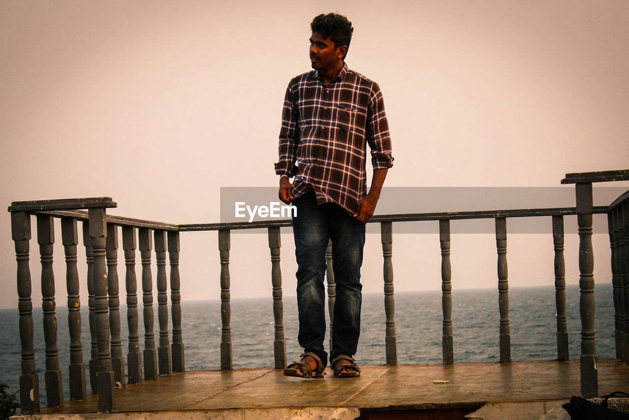 Man standing on observation point over sea against sky