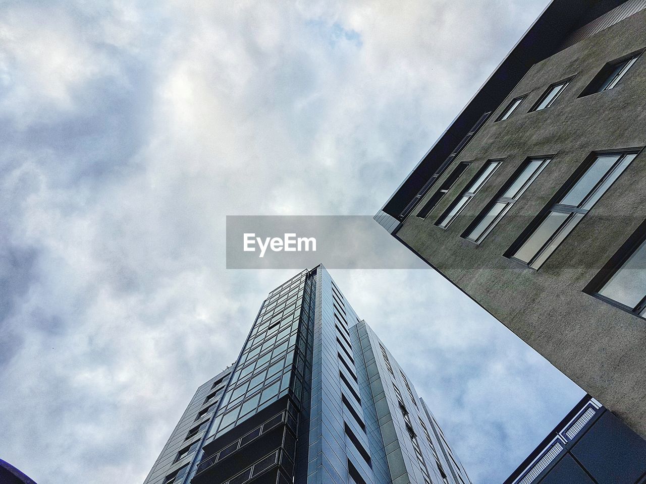 LOW ANGLE VIEW OF MODERN BUILDINGS AGAINST CLOUDY SKY