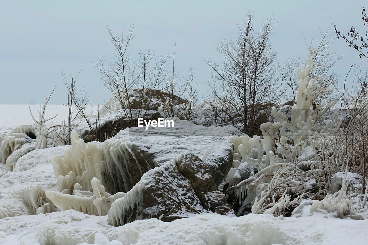 Snow covered rocks on field against sky