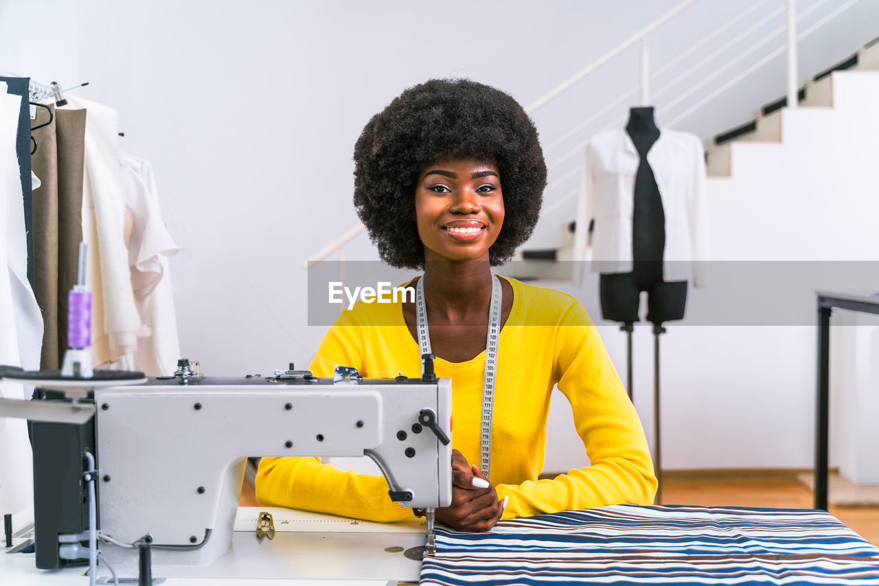 Portrait of smiling fashion designer sitting at boutique