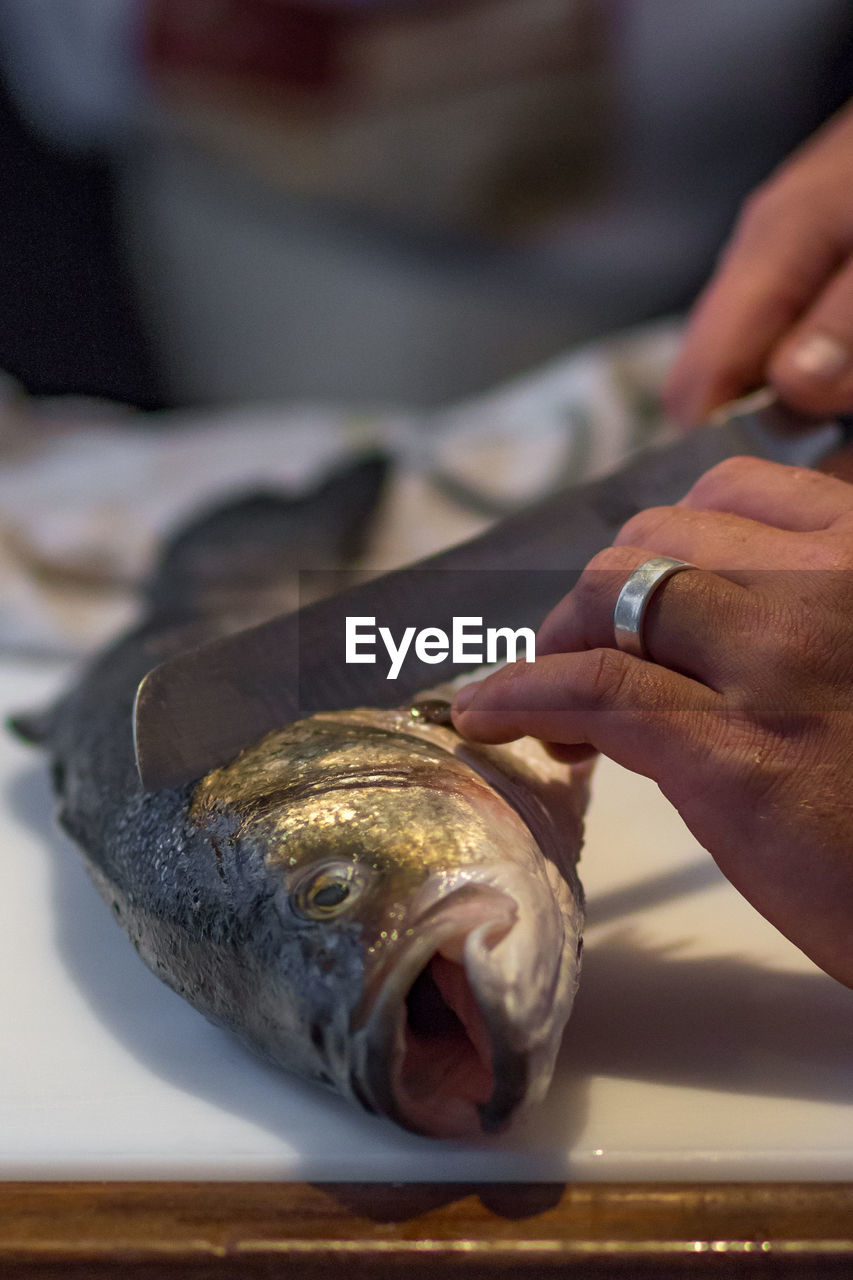 Close-up of hands cutting fish on table