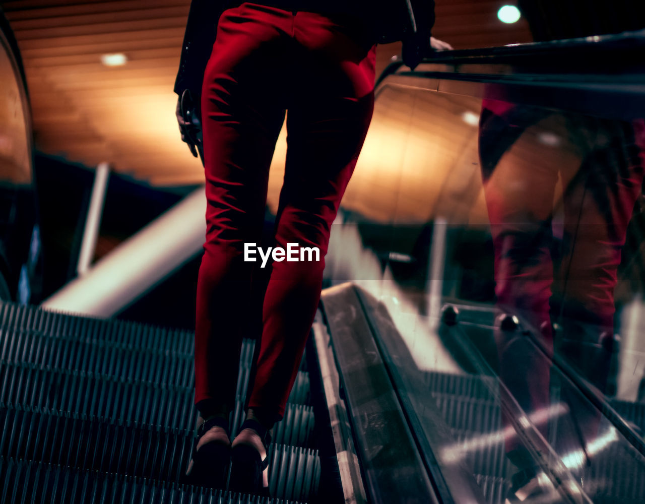 Low section of woman standing on escalator