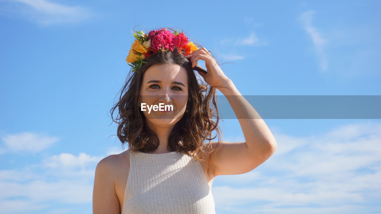 Portrait of beautiful woman standing against sky