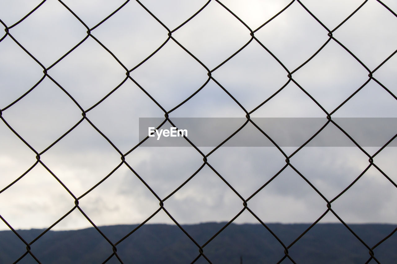 Metal fence background, real fence close-up and texture on the white sky background