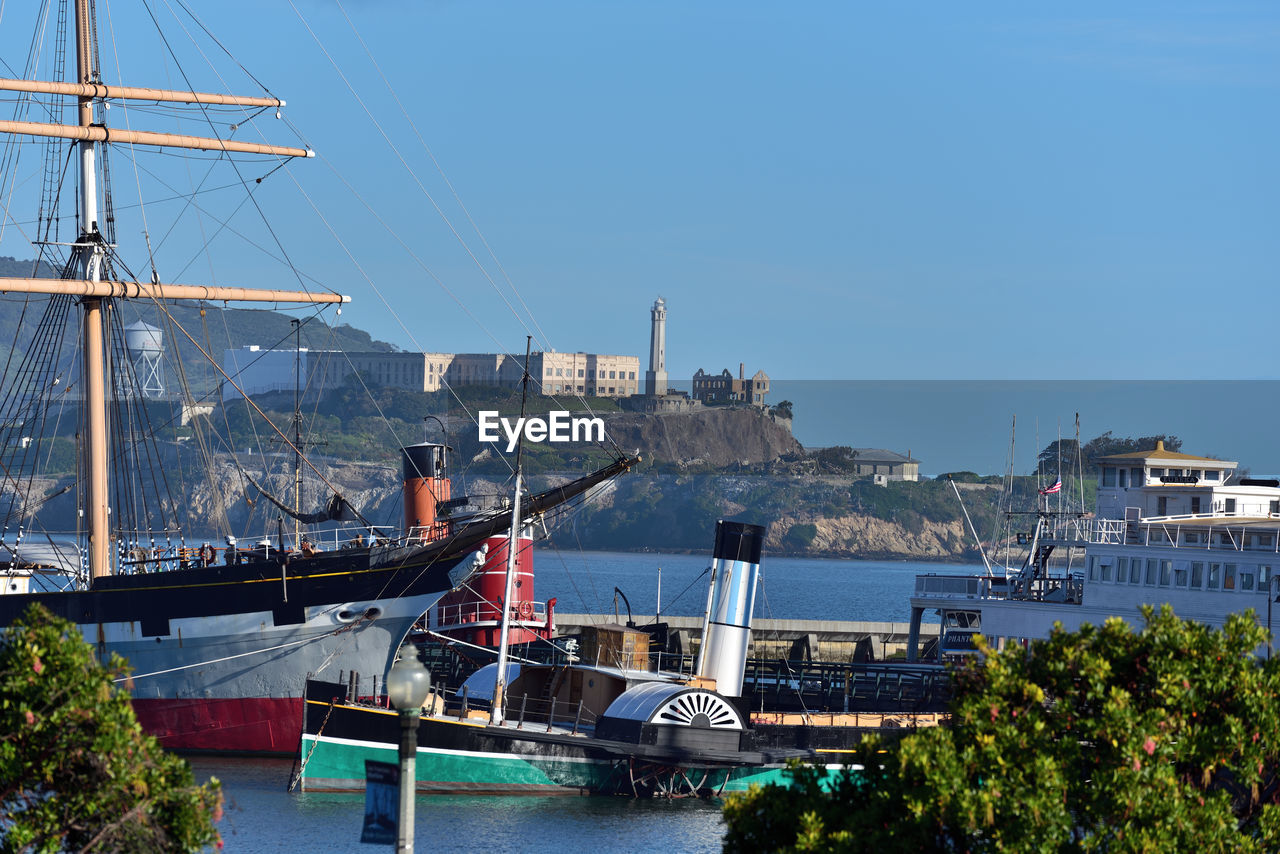 BOATS MOORED AT HARBOR AGAINST CLEAR SKY