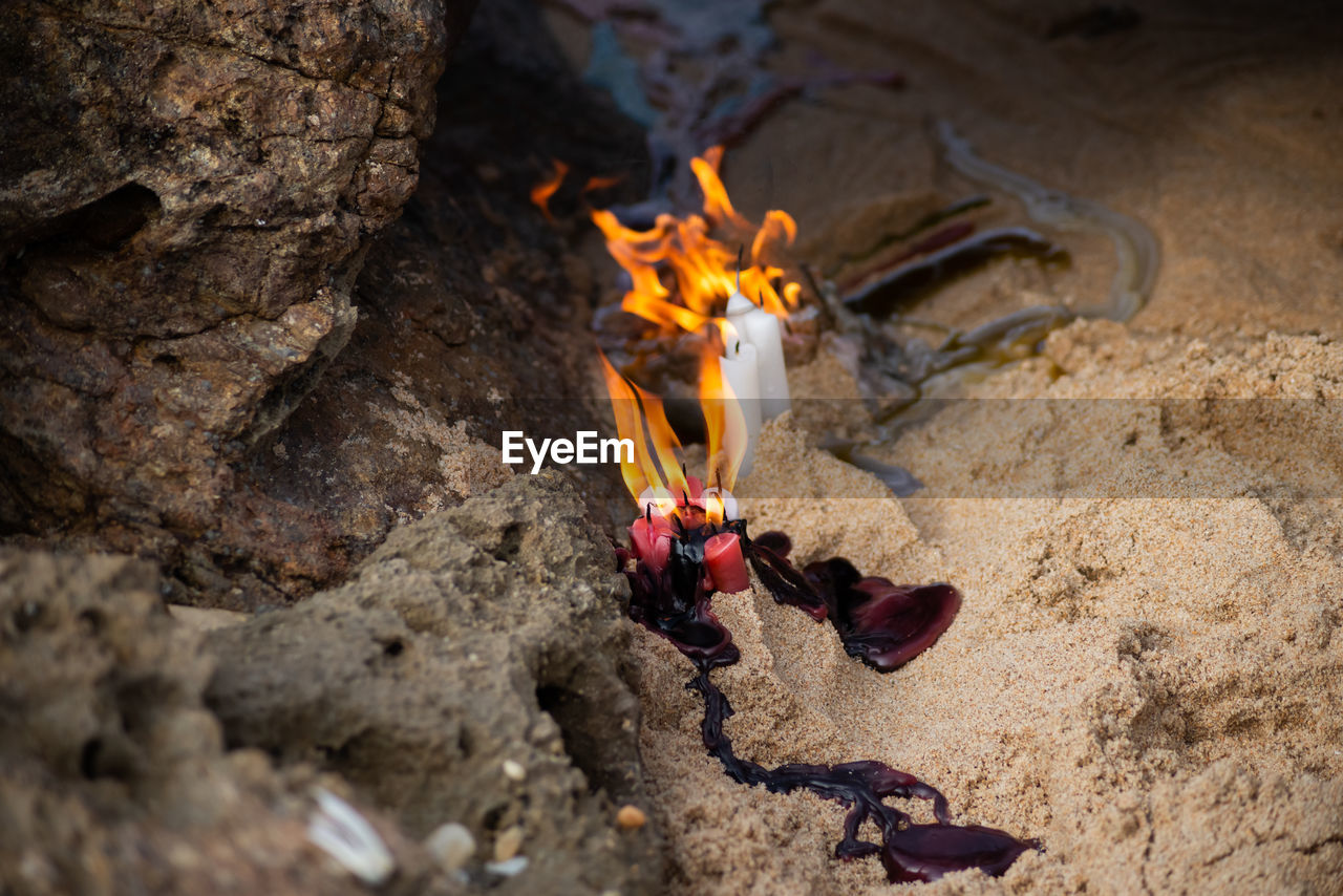 Candles burning among rocks on a beach to honor some religious entity. 