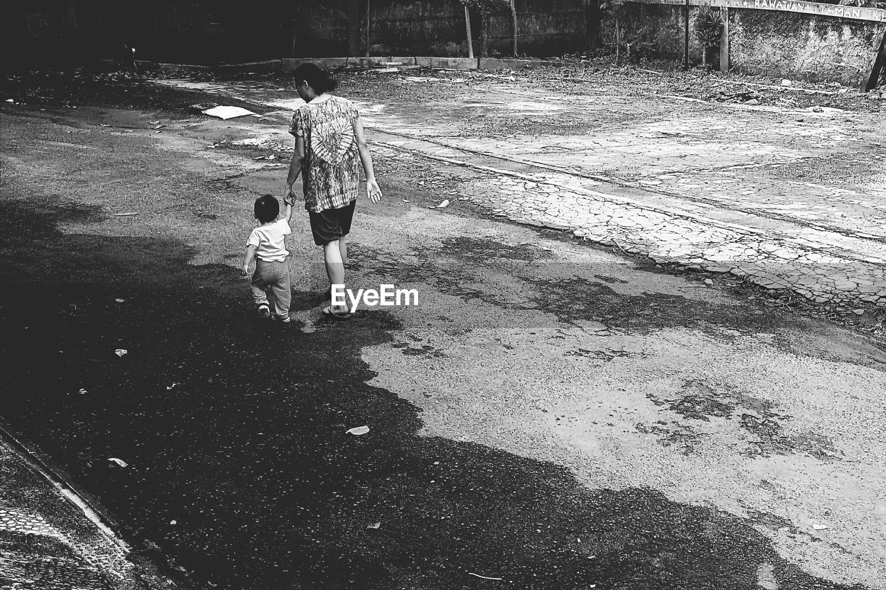 High angle view of mother walking with kid on road