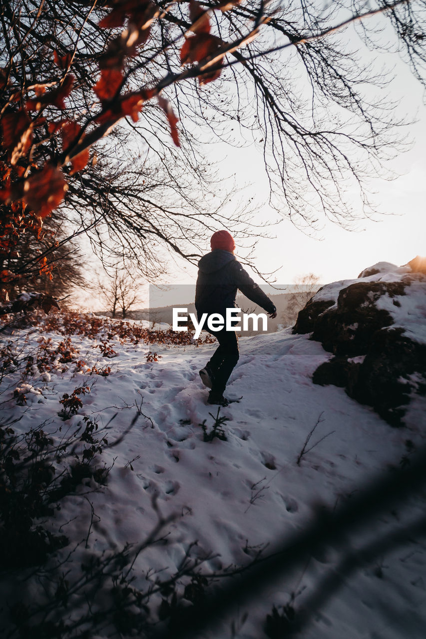 Rear view of girl standing on snow covered field