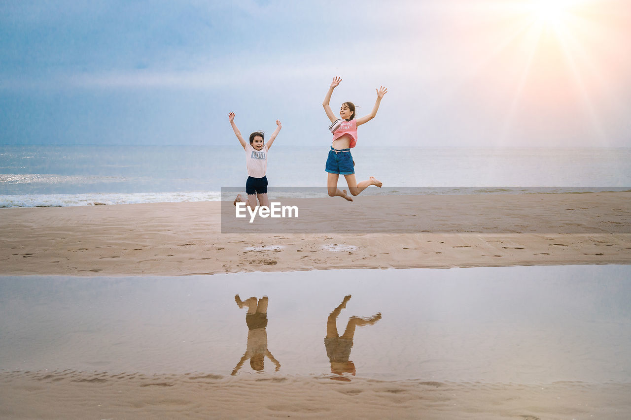 rear view of woman playing with arms outstretched standing at beach