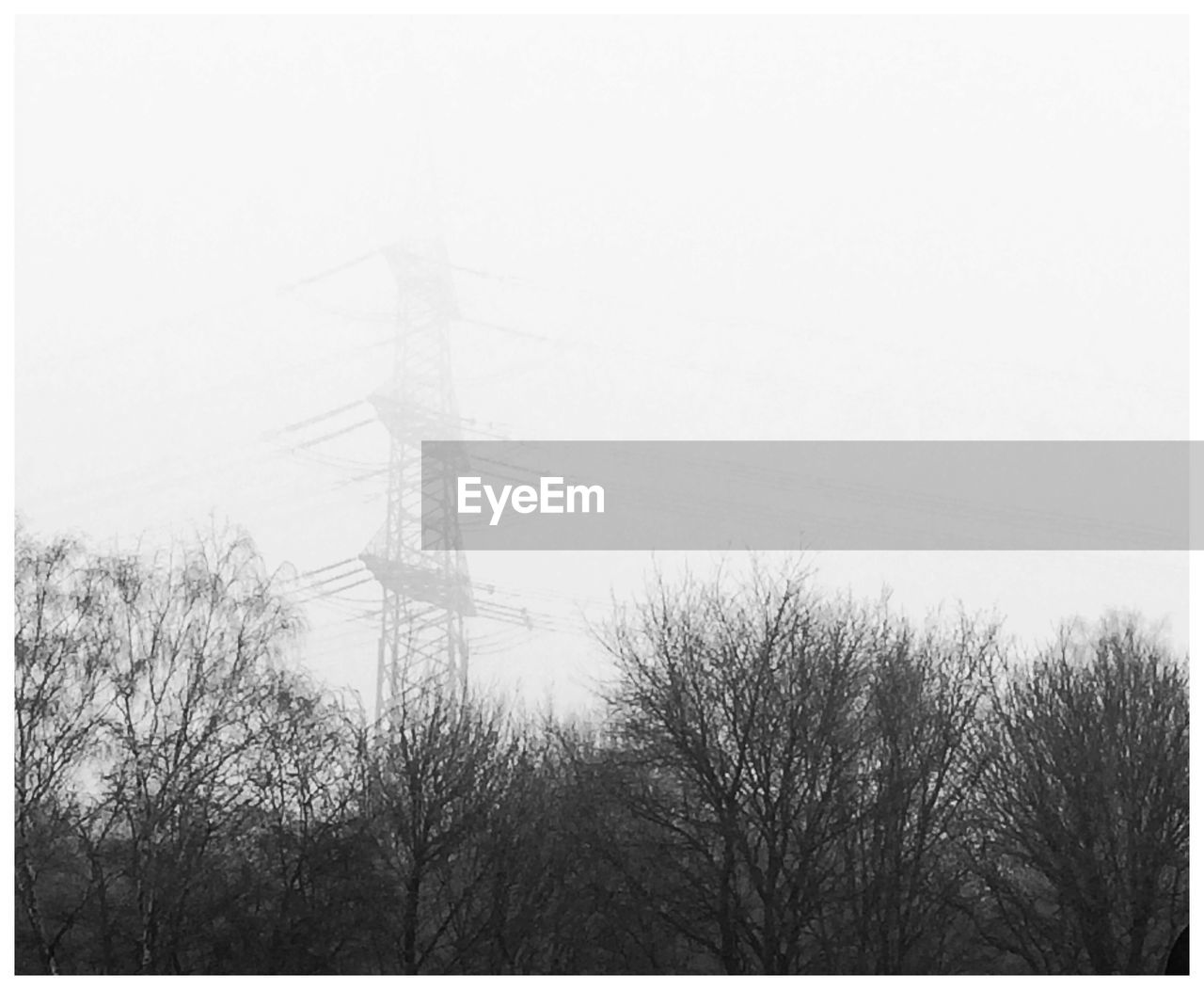 Low angle view of electricity pylon against sky during foggy weather