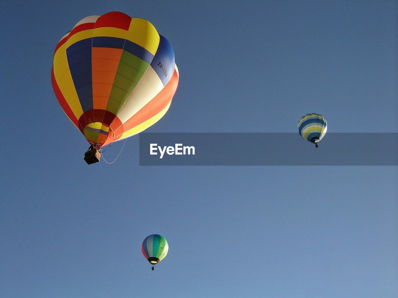 Low angle view of hot air balloons in clear blue sky