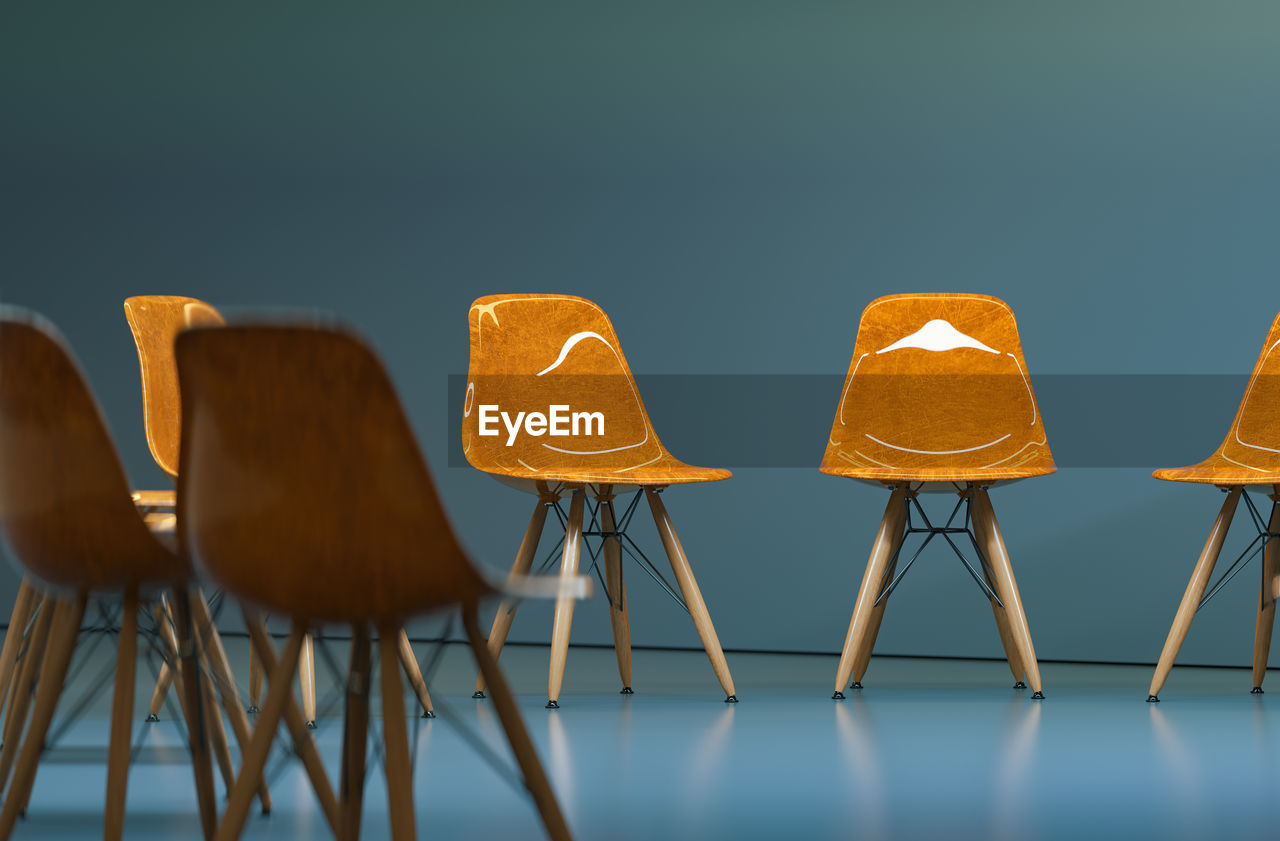 Close-up of empty chairs on floor against wall