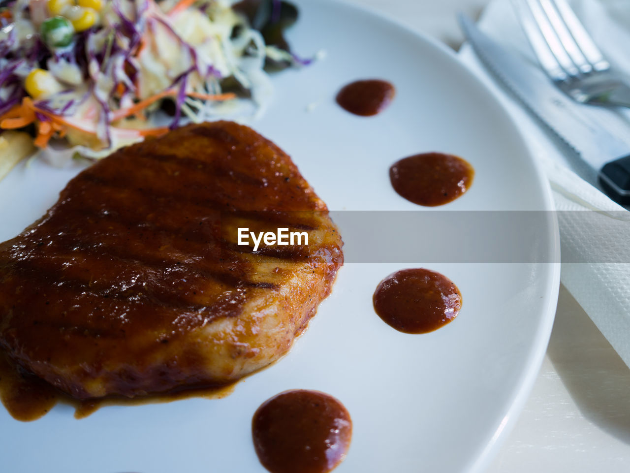 Close-up of pork chop with barbeque sauce in plate served on table