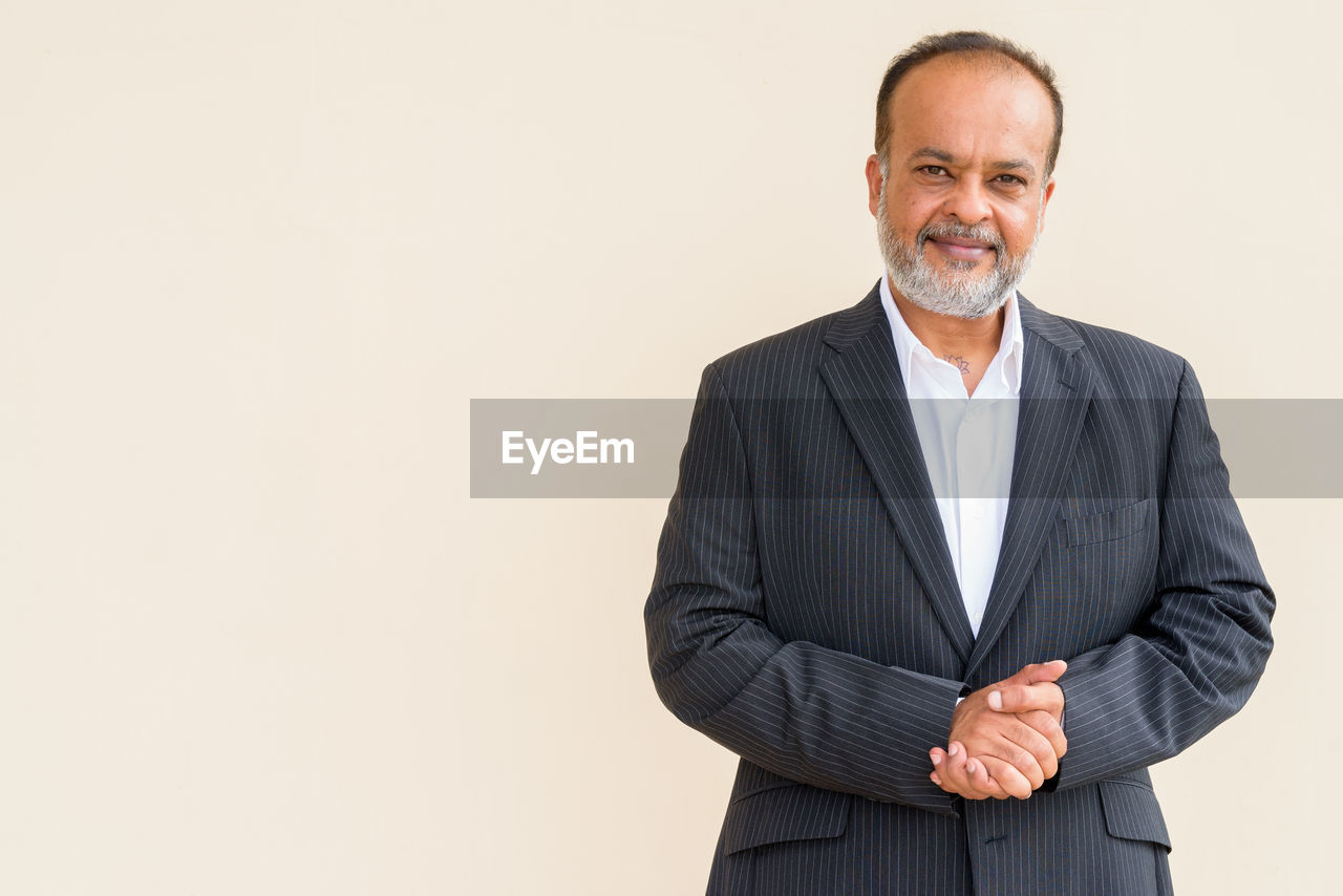 PORTRAIT OF A SMILING MAN AGAINST GRAY BACKGROUND