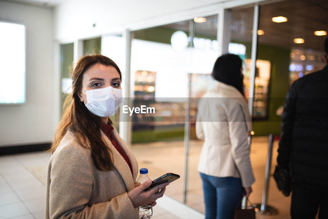 Young woman wearing mask standing at mall