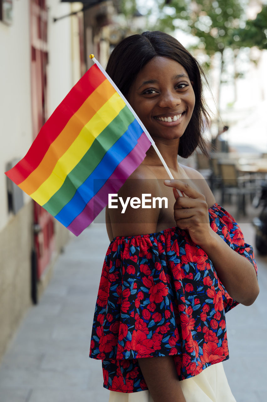 Happy young woman holding rainbow flag