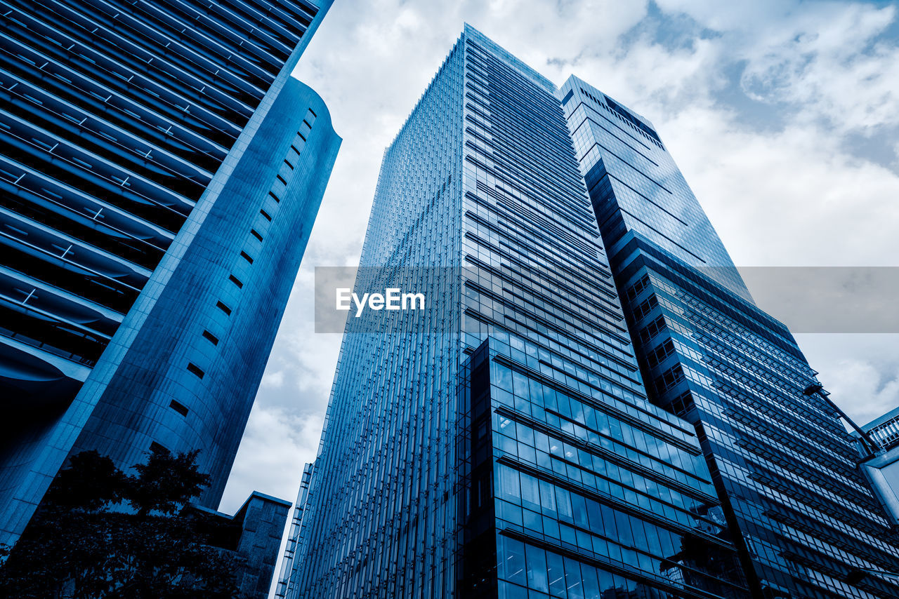 LOW ANGLE VIEW OF MODERN GLASS BUILDING AGAINST SKY