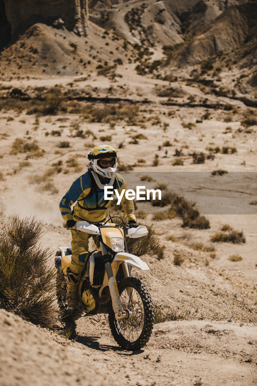 Sportsperson riding enduro motorcycle in desert during sunny day