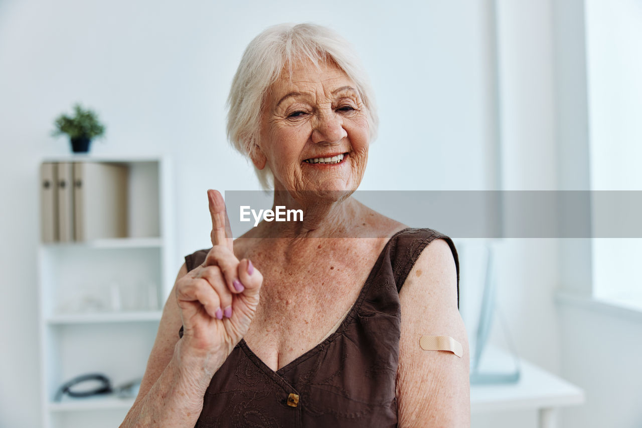 Smiling senior woman gesturing at hospital