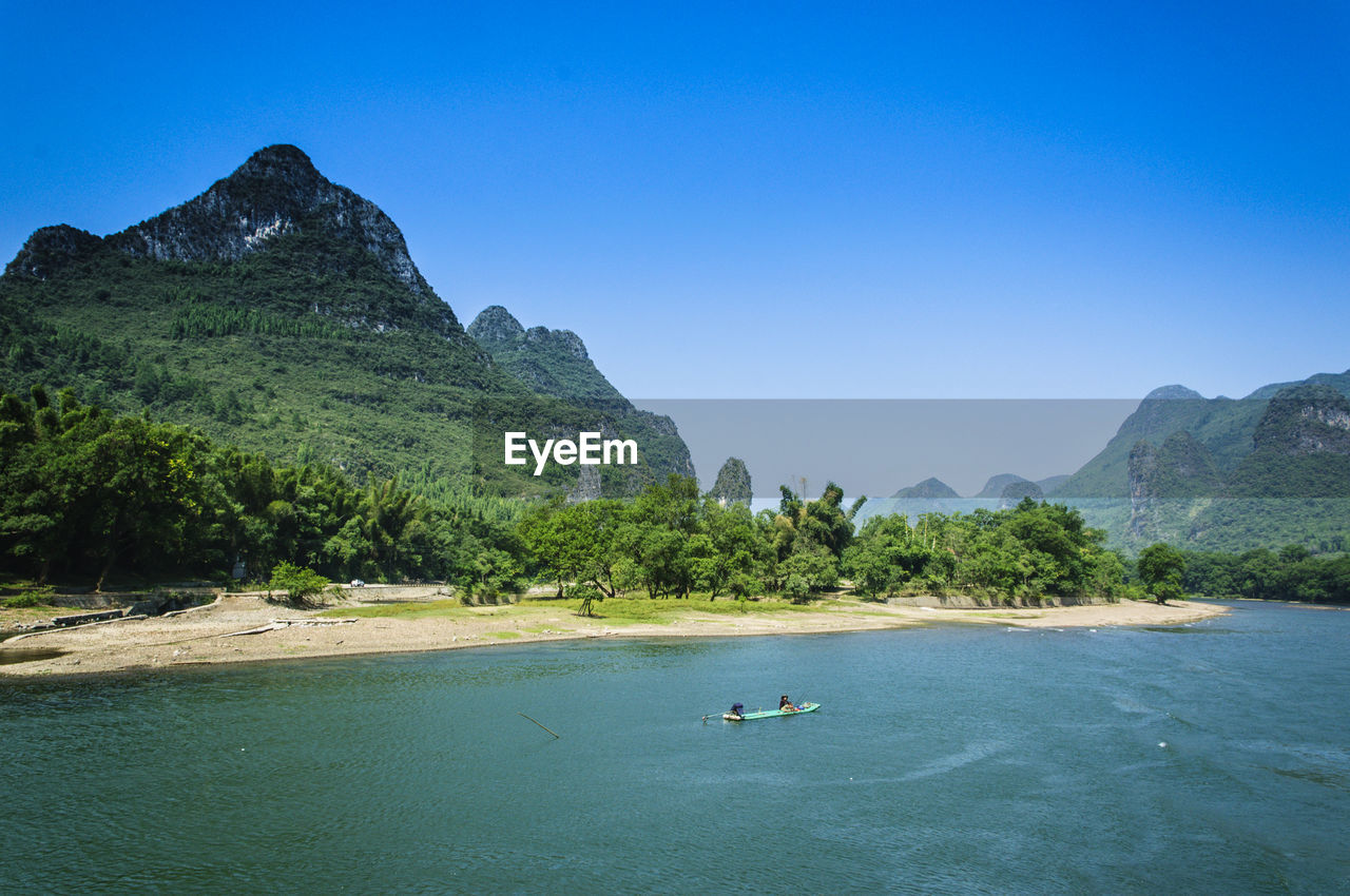 SCENIC VIEW OF SEA BY MOUNTAIN AGAINST CLEAR BLUE SKY