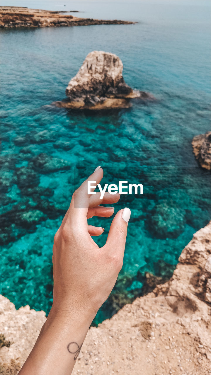 Cropped hand of woman reaching sea