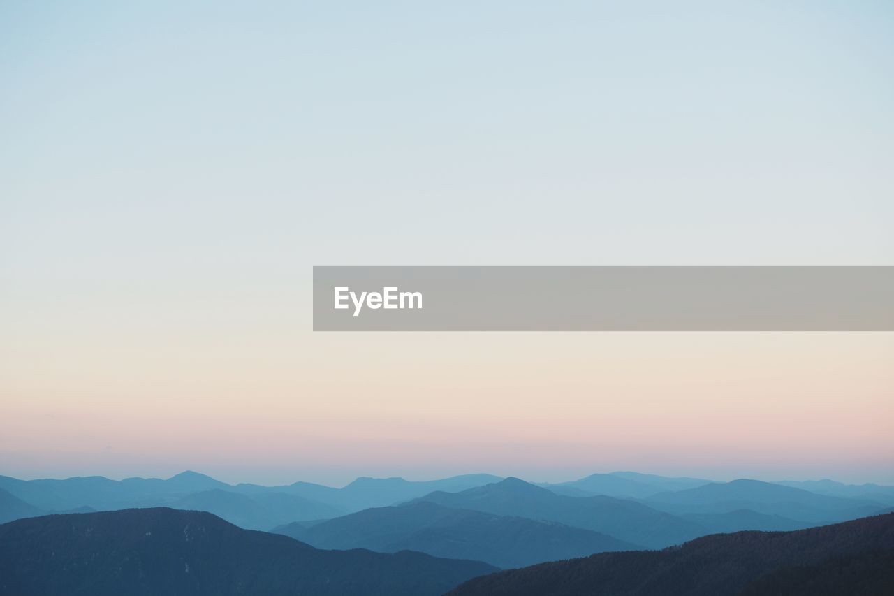 SCENIC VIEW OF SILHOUETTE MOUNTAINS AGAINST CLEAR SKY AT SUNSET