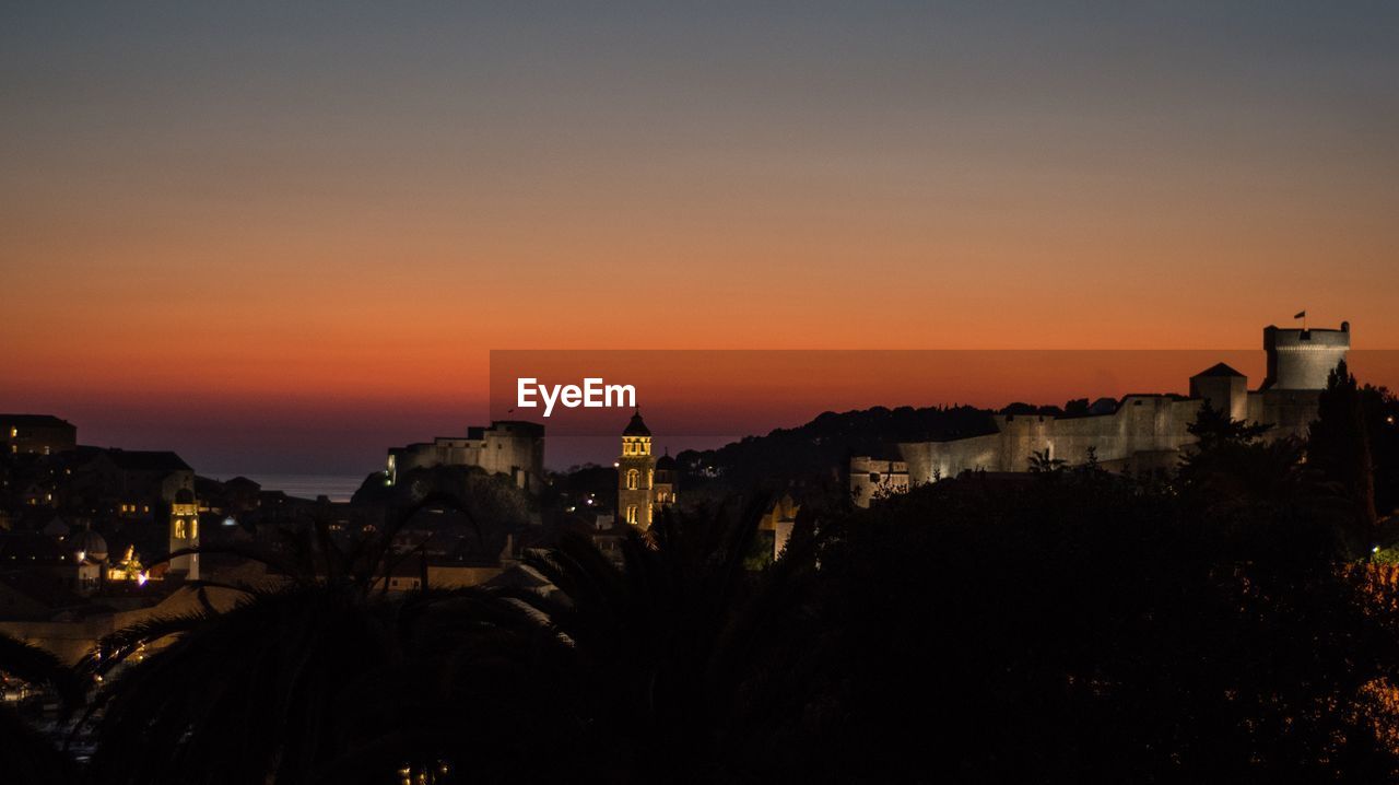 SILHOUETTE BUILDINGS AGAINST SKY AT SUNSET
