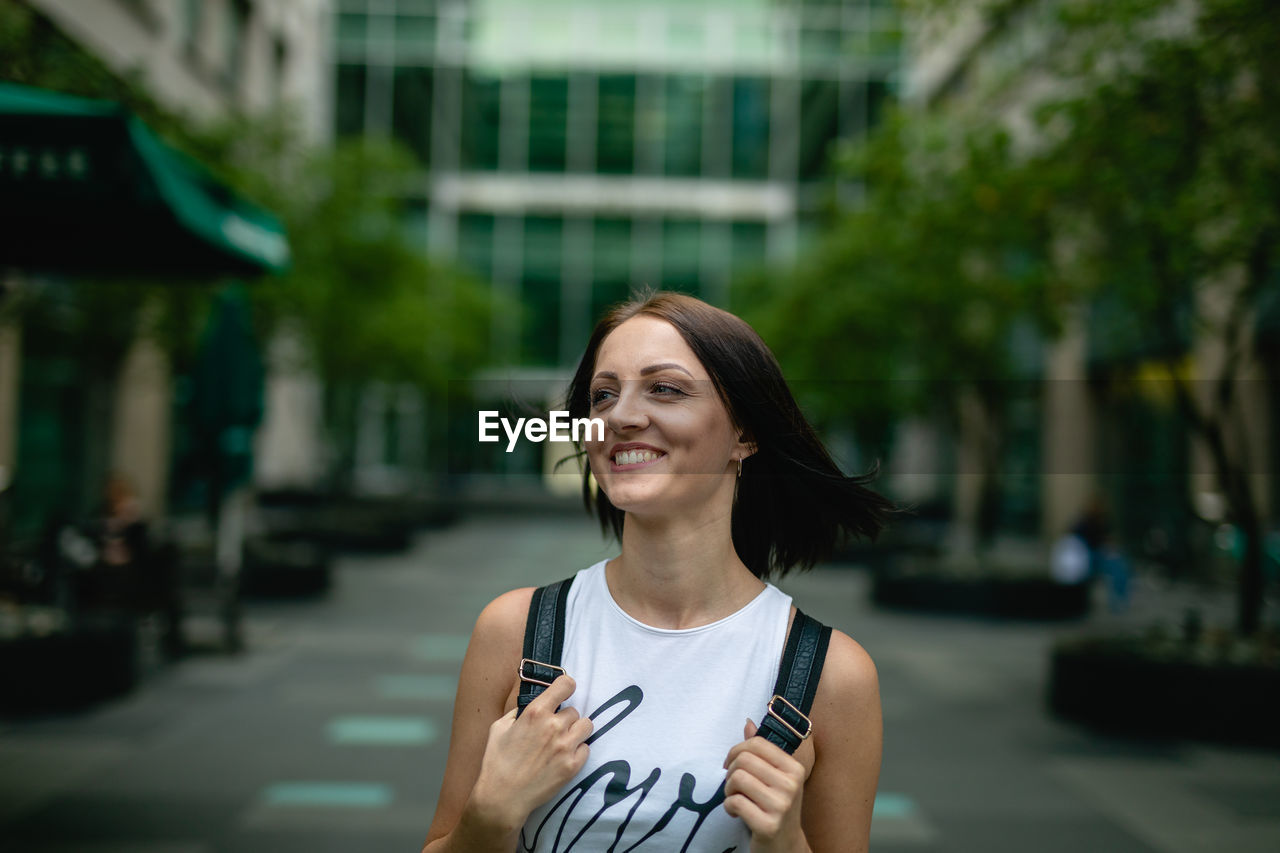 Happy young woman walking on footpath in city