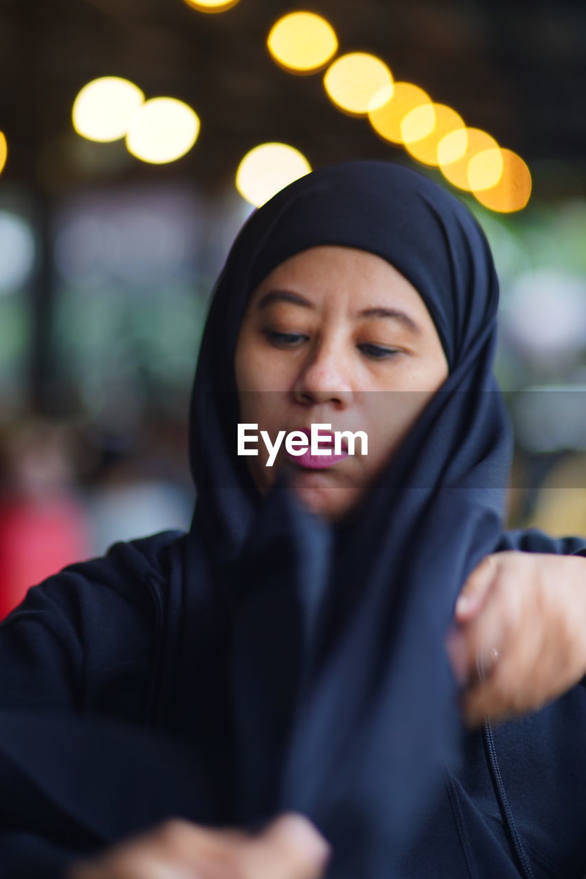 Portrait of indonesian muslim woman wearing black hijab with bokeh.