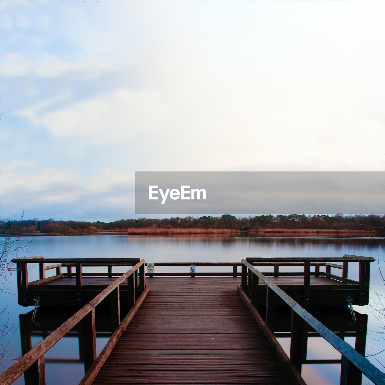 Empty pier over lake against sky