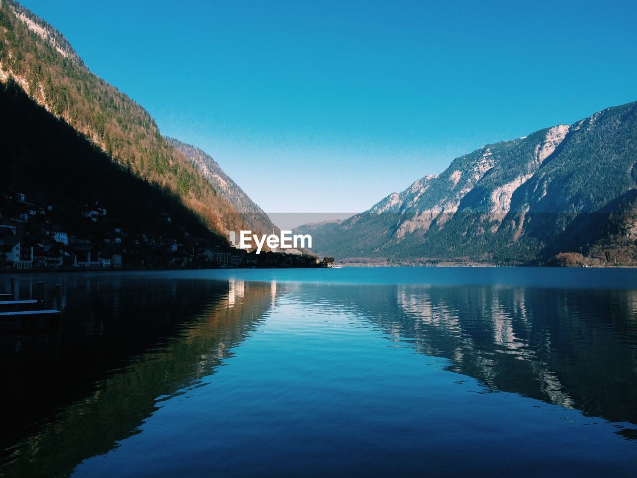 Scenic view of lake and mountains against clear blue sky