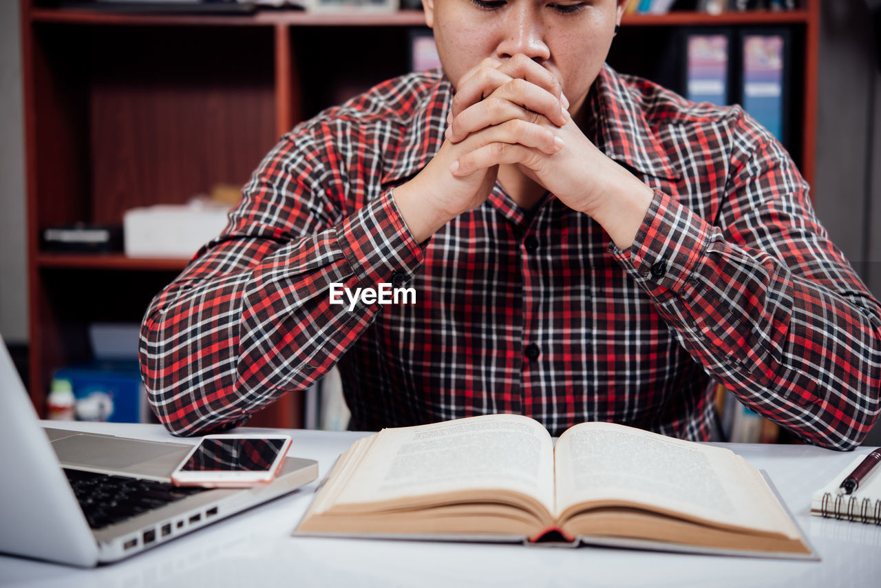 MIDSECTION OF MAN USING LAPTOP