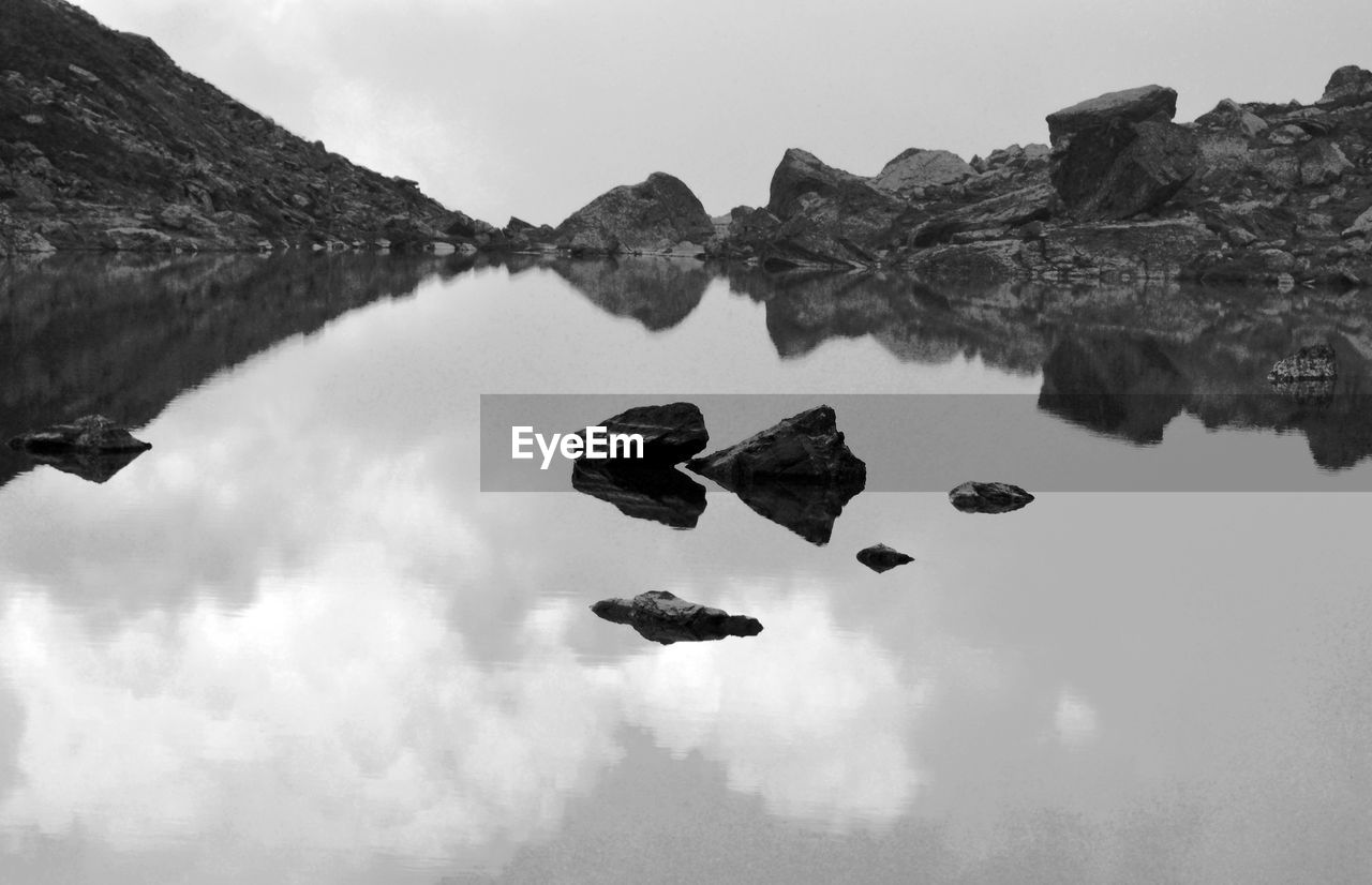 Reflection of rocks in lake against sky